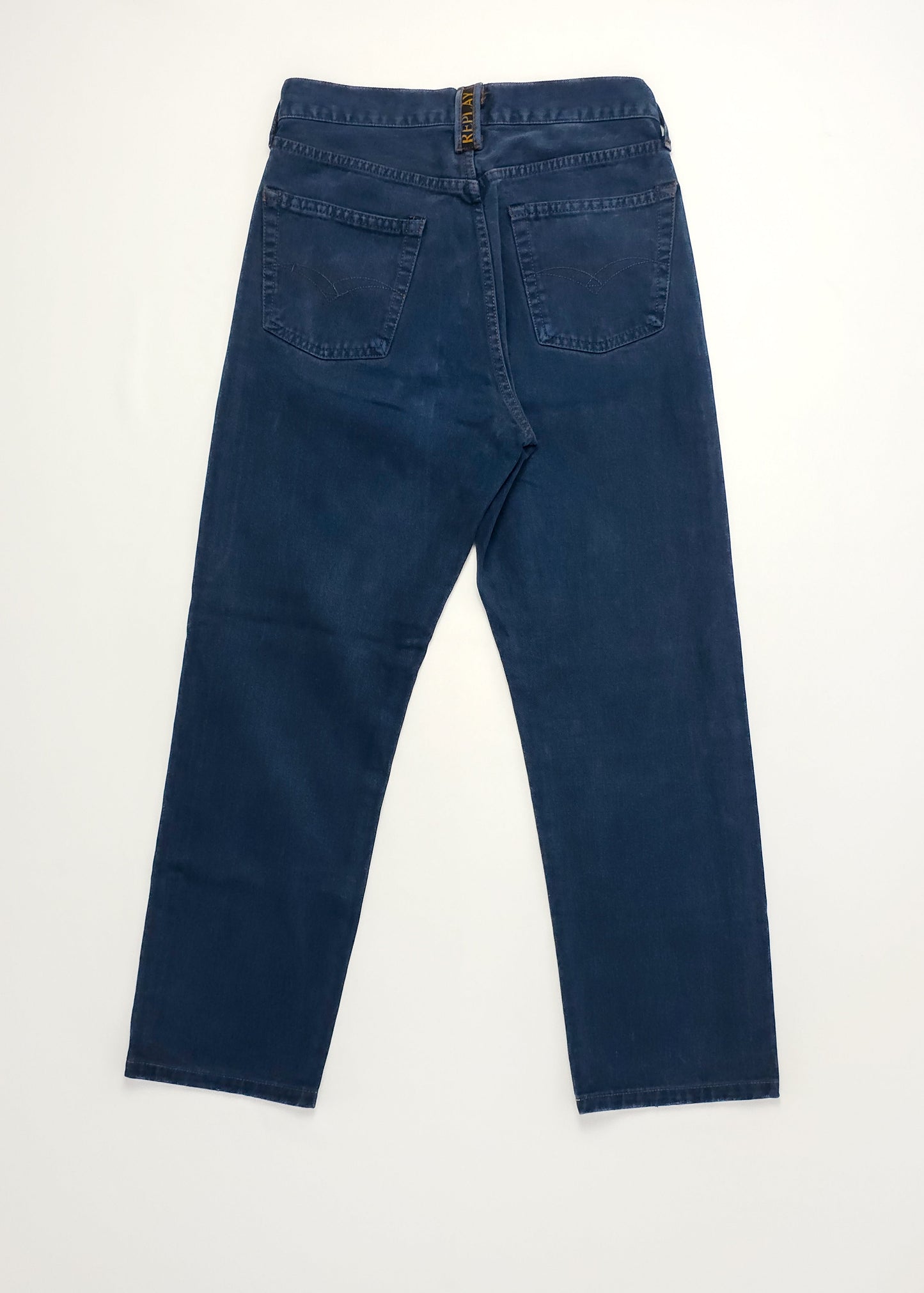 Back view of high-waisted, dark blue denim jeans with a zipper closure and two back pockets, laid flat on a white surface.