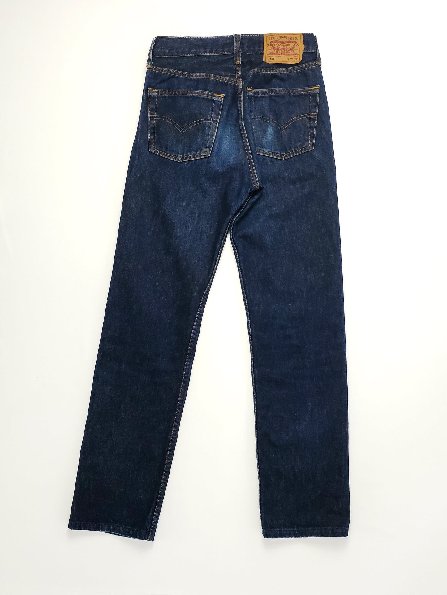 Dark blue denim jeans with a straight leg fit, featuring back pockets and a leather patch on the waistband, laid flat on a white background.