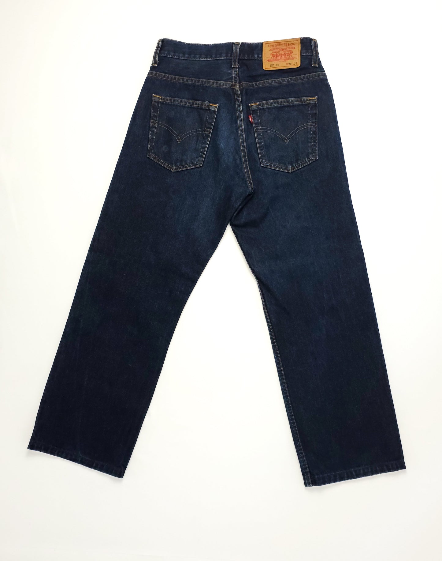 Dark blue denim jeans displayed on a white background, featuring two back pockets with stitching details and a leather patch on the waistband.