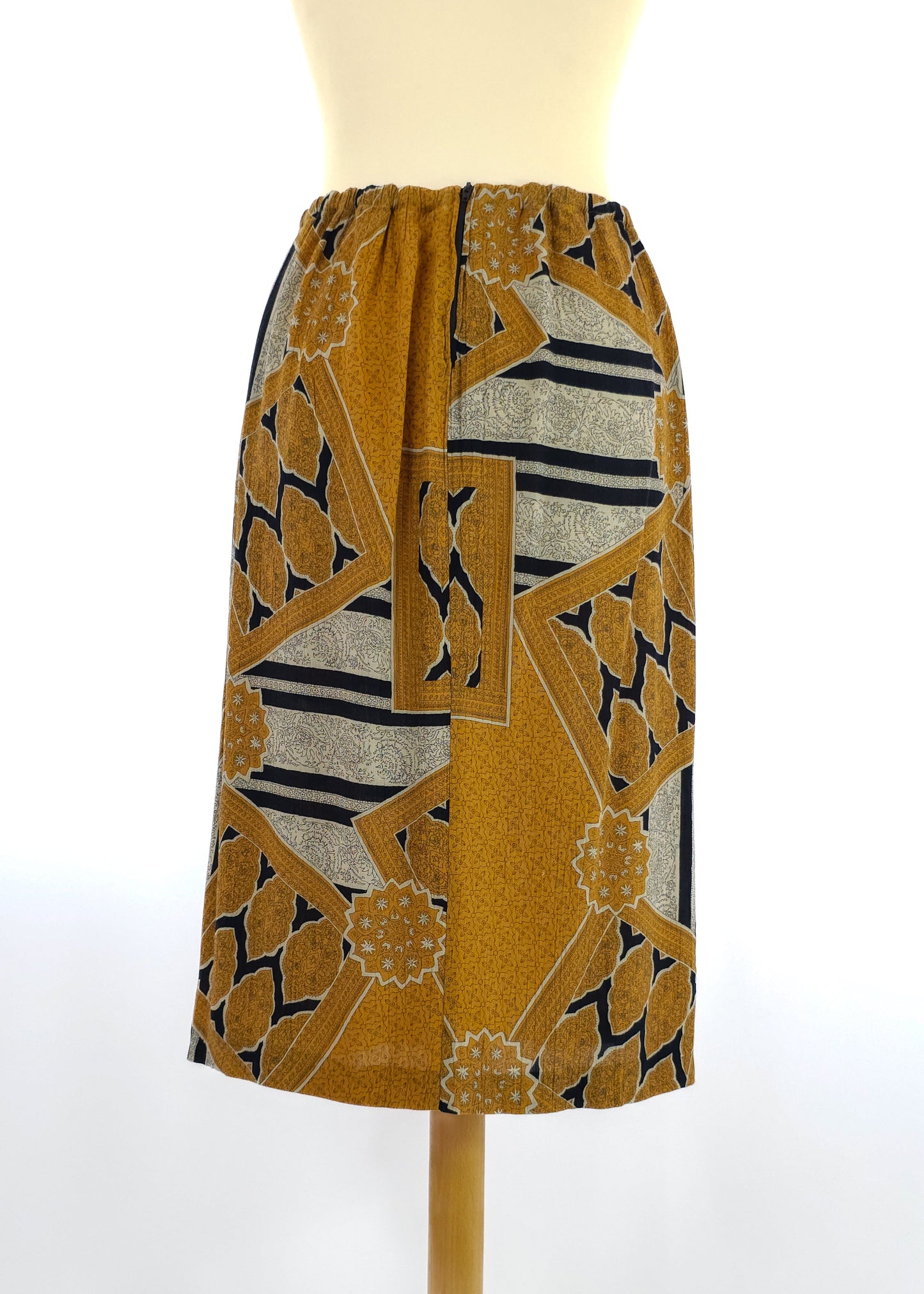 A knee-length skirt with an elastic waistband featuring a bold geometric pattern in mustard yellow, black, and beige colors.