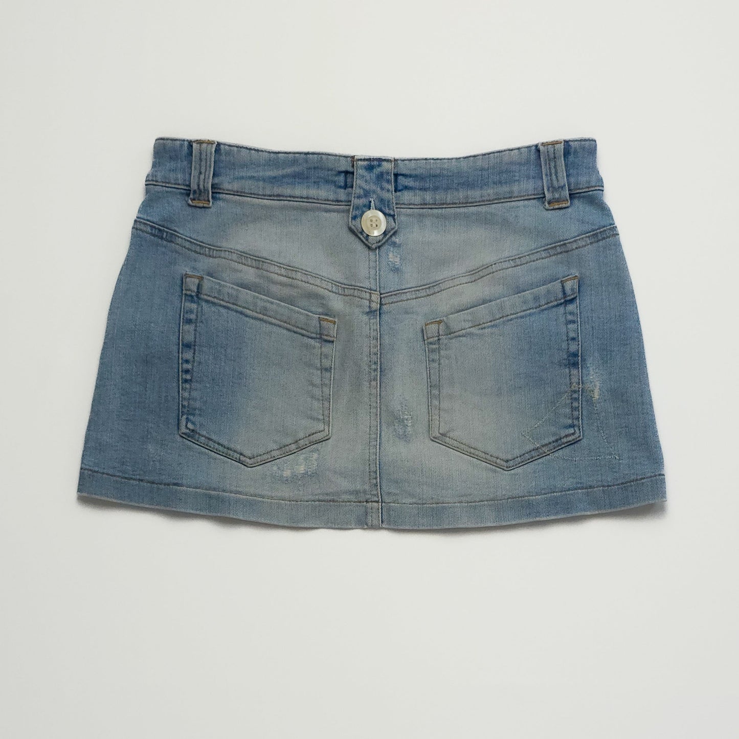 A light blue denim mini skirt with front button closure and two back pockets, laid flat. The skirt has a slightly faded, worn-in look.