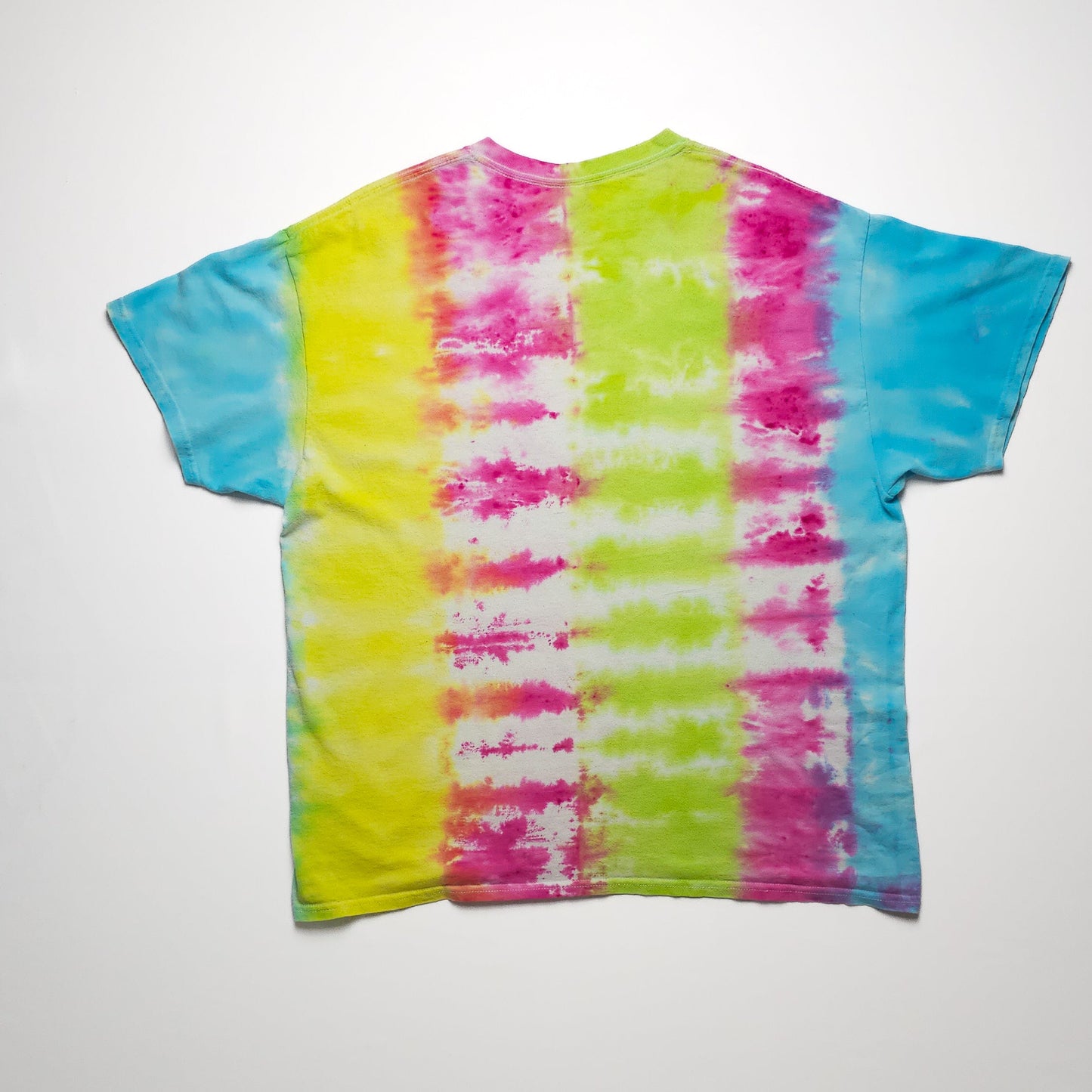 A colorful tie-dye T-shirt featuring vertical stripes in pink, yellow, green, and blue. The pattern is symmetrical with vibrant, bold colors against a white background.