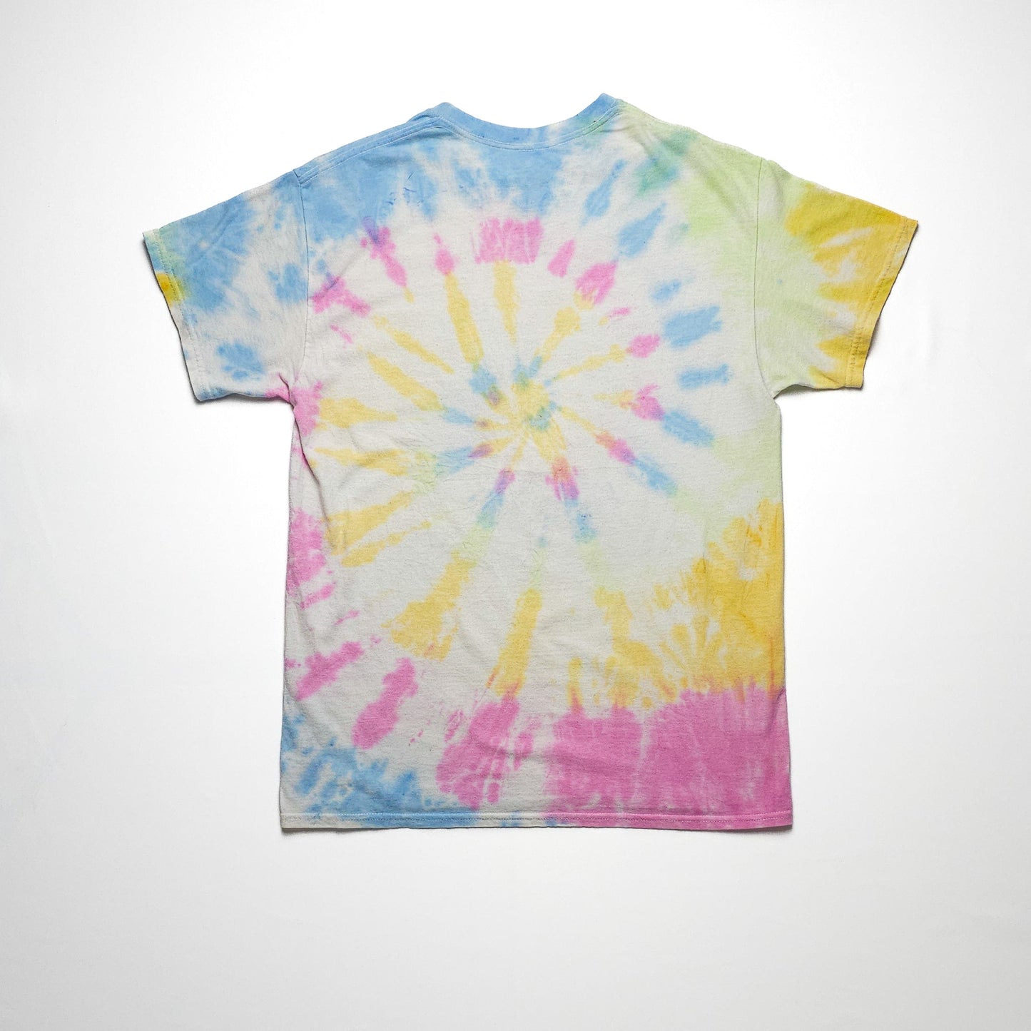 A colorful tie-dye t-shirt with spiral patterns in shades of pink, yellow, blue, and green against a white background, laid flat and viewed from the back.