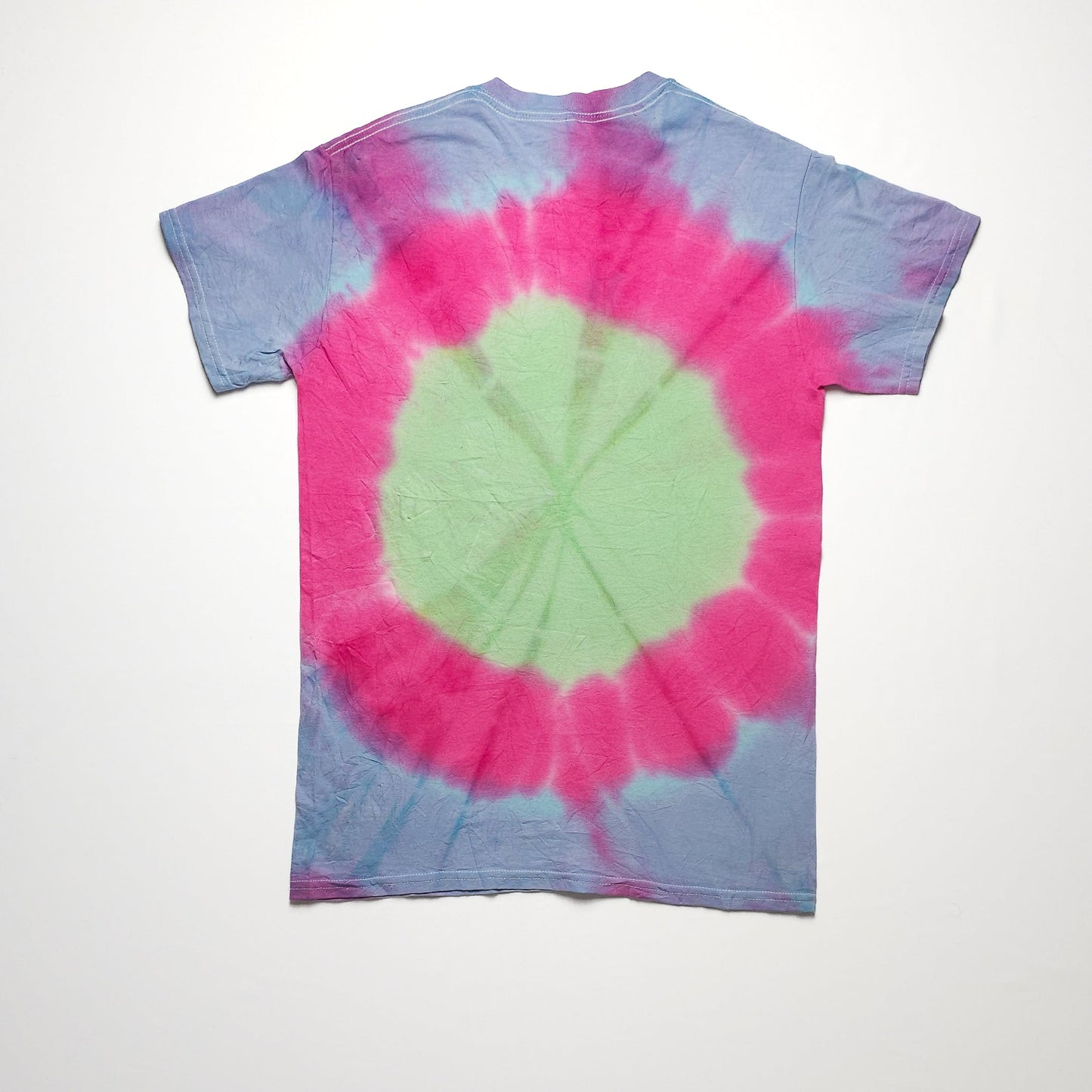 A colorful tie-dye T-shirt with a large circular pattern, featuring pink, blue, and green hues, spread evenly across the fabric.