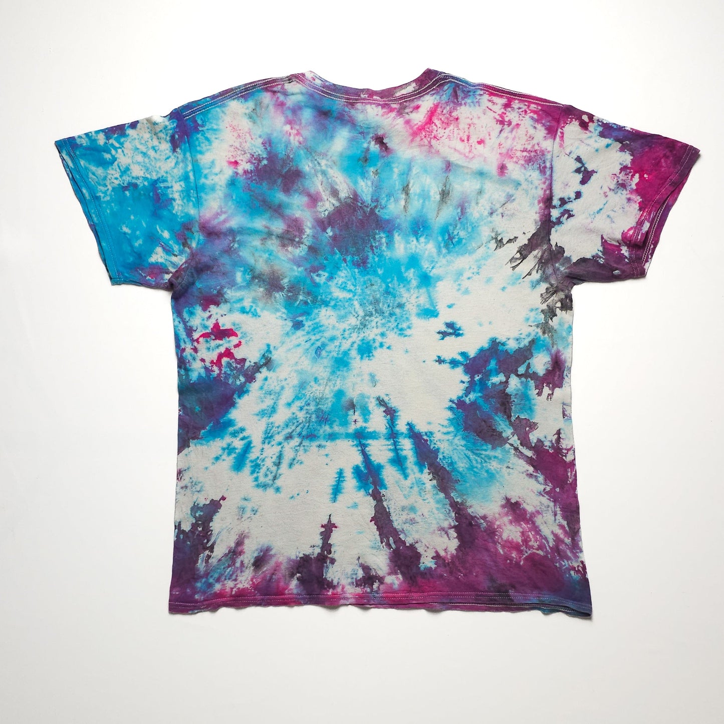 A colorful tie-dye t-shirt featuring a blend of vibrant blue, pink, and purple hues with a spiral pattern on a plain background.