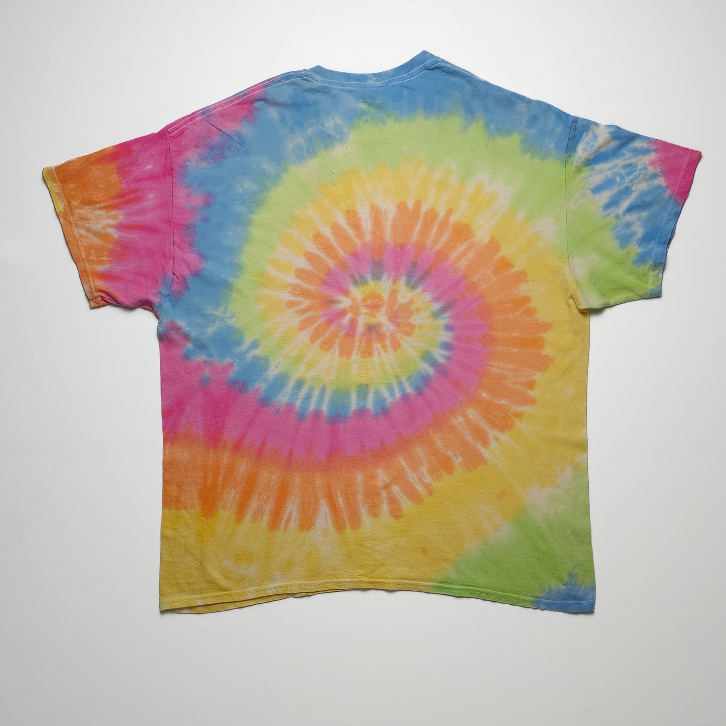 A colorful tie-dye T-shirt featuring a spiral pattern with vibrant hues of blue, yellow, pink, orange, and green, spread across the entire shirt.