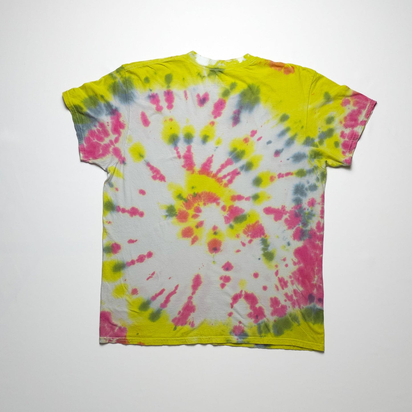 A colorful tie-dye t-shirt with a spiral pattern in yellow, pink, blue, and white. The shirt has short sleeves and a round neck, with vibrant hues.