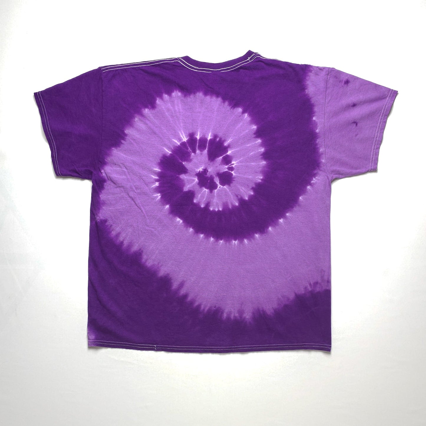 A purple tie-dye t-shirt with a spiral pattern, featuring various shades of purple creating a dynamic, swirling design on the fabric.