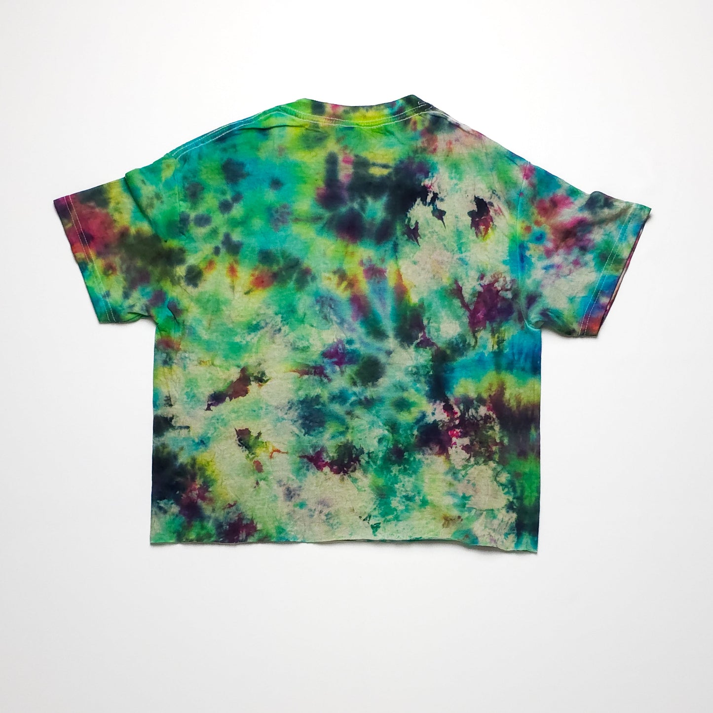 A colorful tie-dye T-shirt with a blend of green, blue, yellow, pink, and purple hues. The T-shirt has a relaxed fit and short sleeves, displayed on a white background.