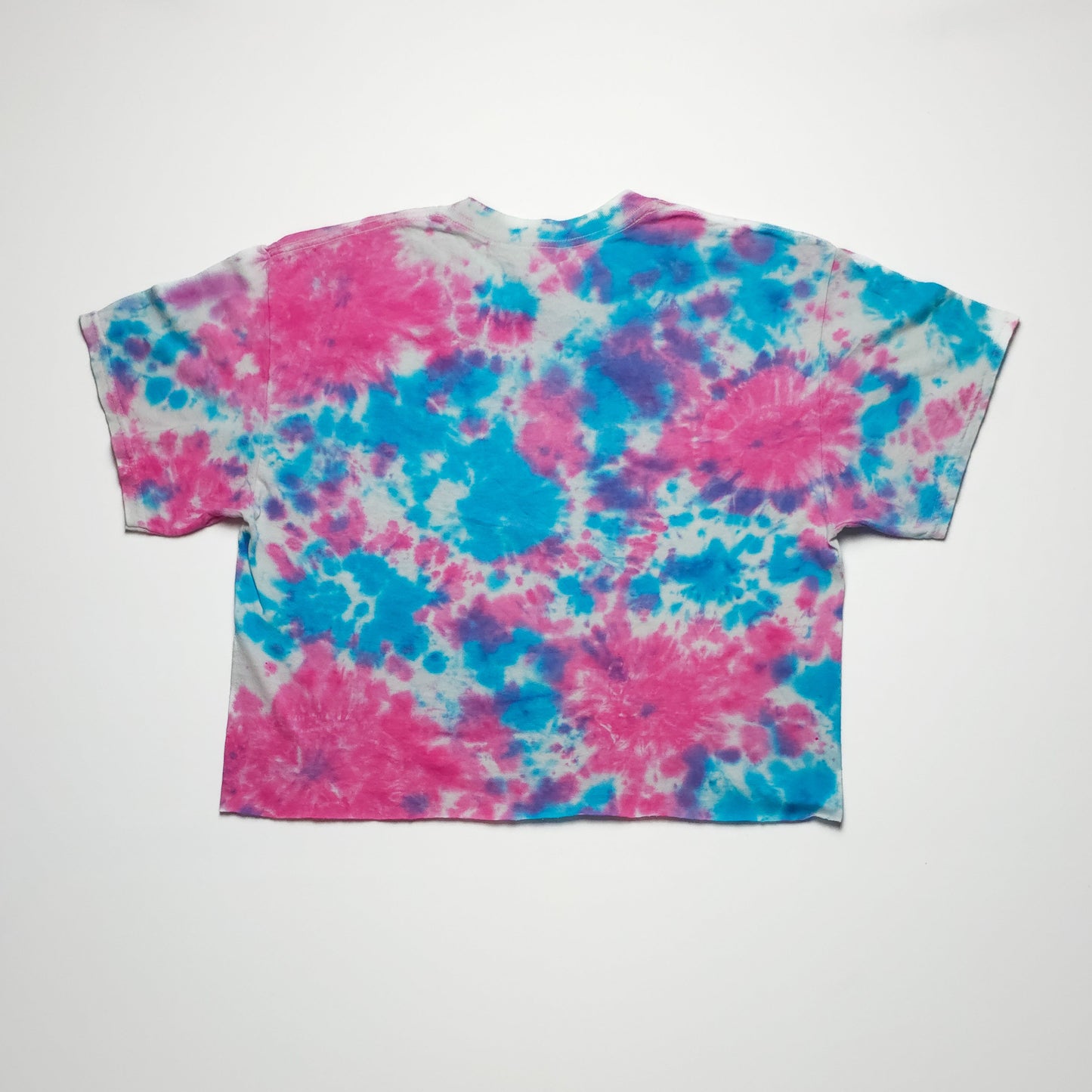 A multicolored tie-dye t-shirt featuring a blend of pink, blue, and white patterns. The shirt has a relaxed, loose fit with short sleeves.
