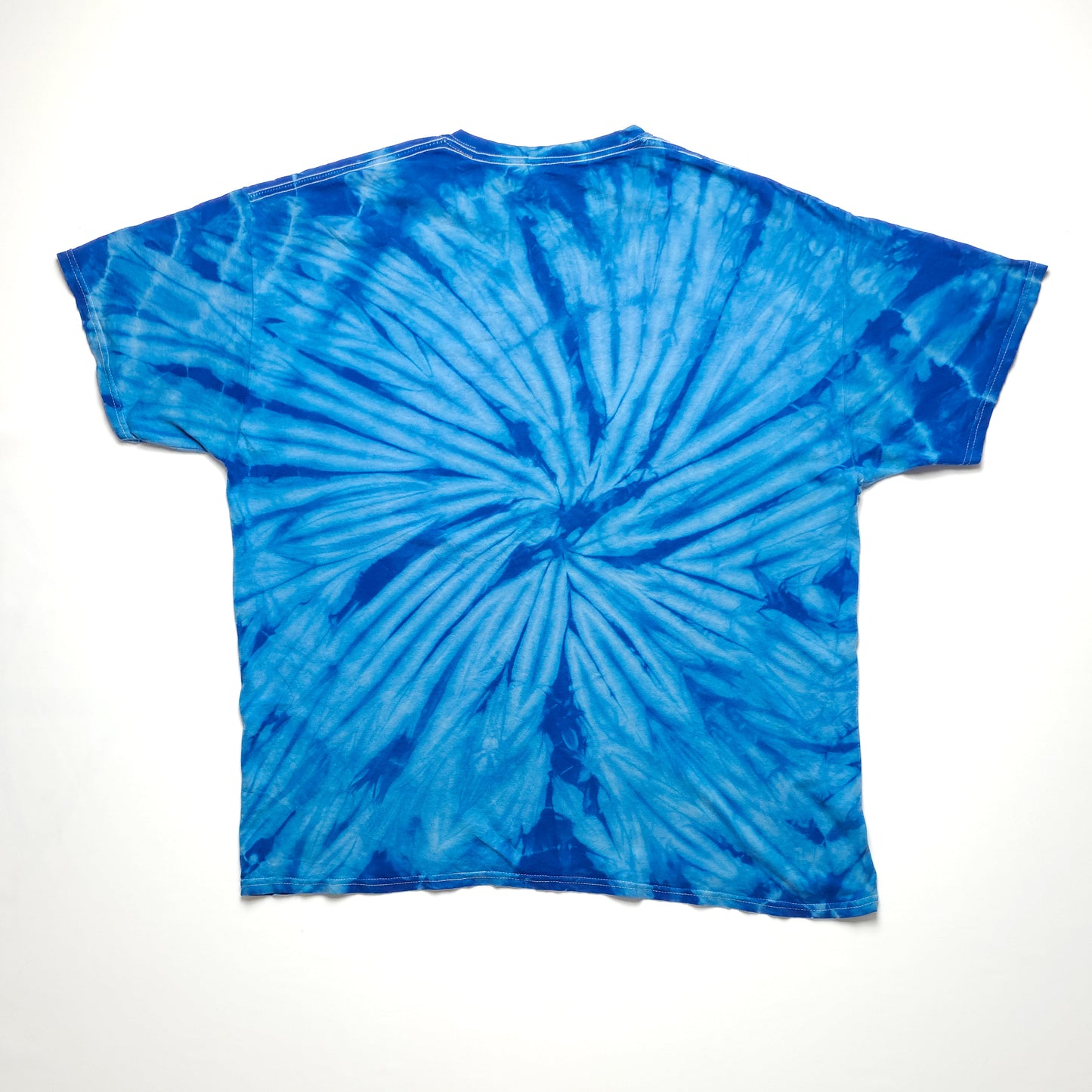 Blue tie-dye t-shirt with circular patterns, laid flat on a white background. The shirt features a vibrant mix of light and dark blue shades.
