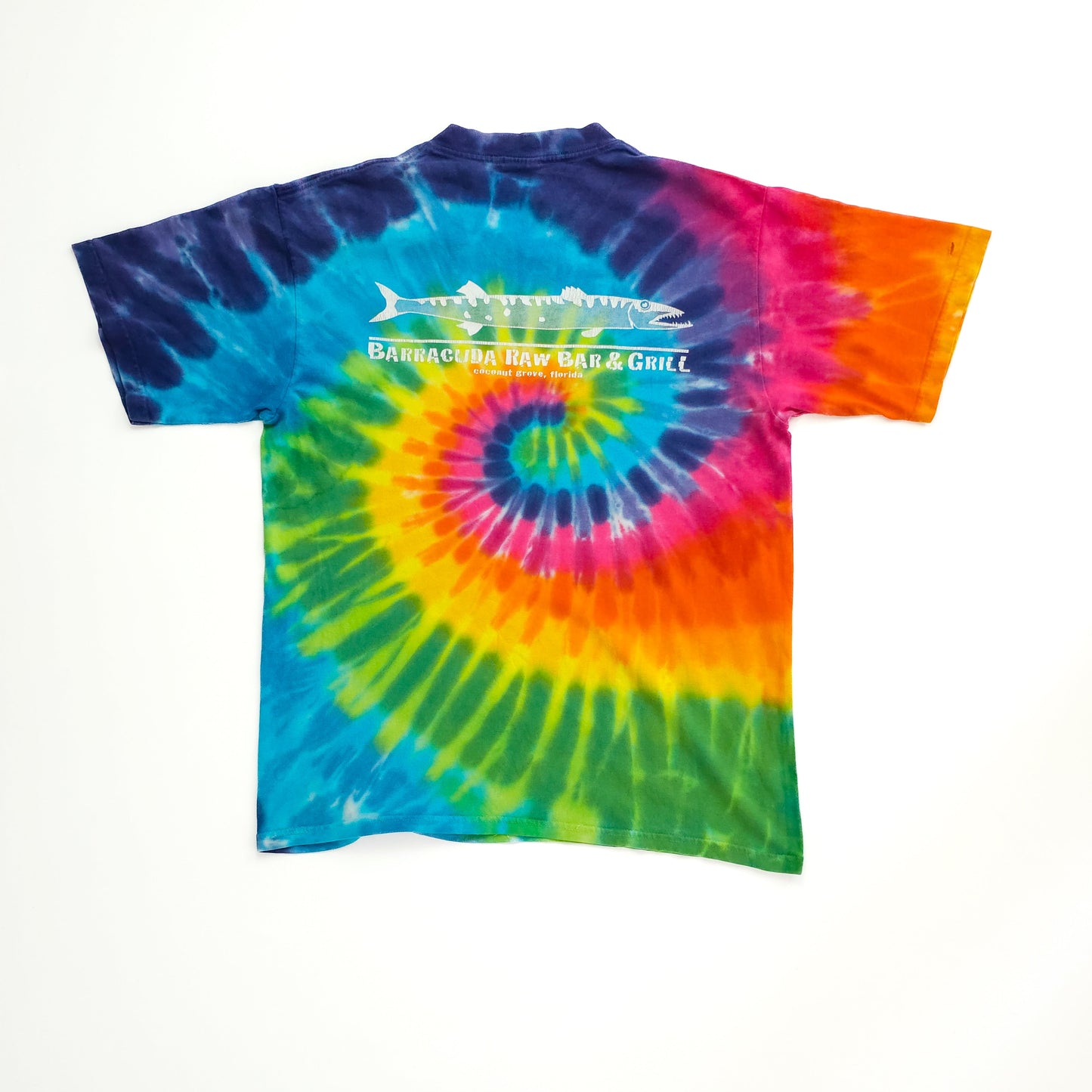 Colorful tie-dye t-shirt featuring a swirl pattern in blue, green, yellow, and pink. Text and image of a fish on the back read "Barracuda Raw Bar & Grill."