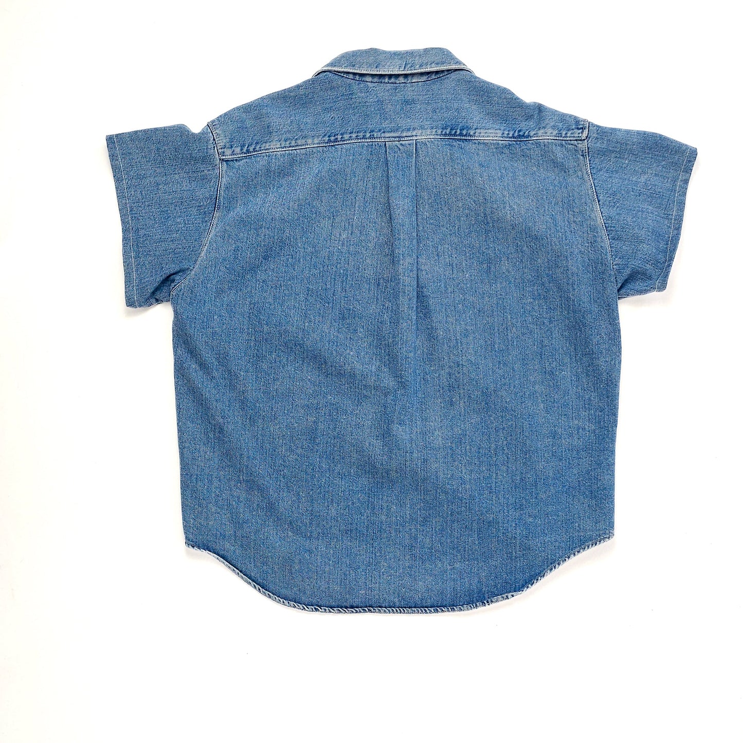 A blue denim short-sleeve shirt with rolled cuffs and a classic collar, shown from the back. The shirt has a relaxed fit and a yoke across the shoulders.