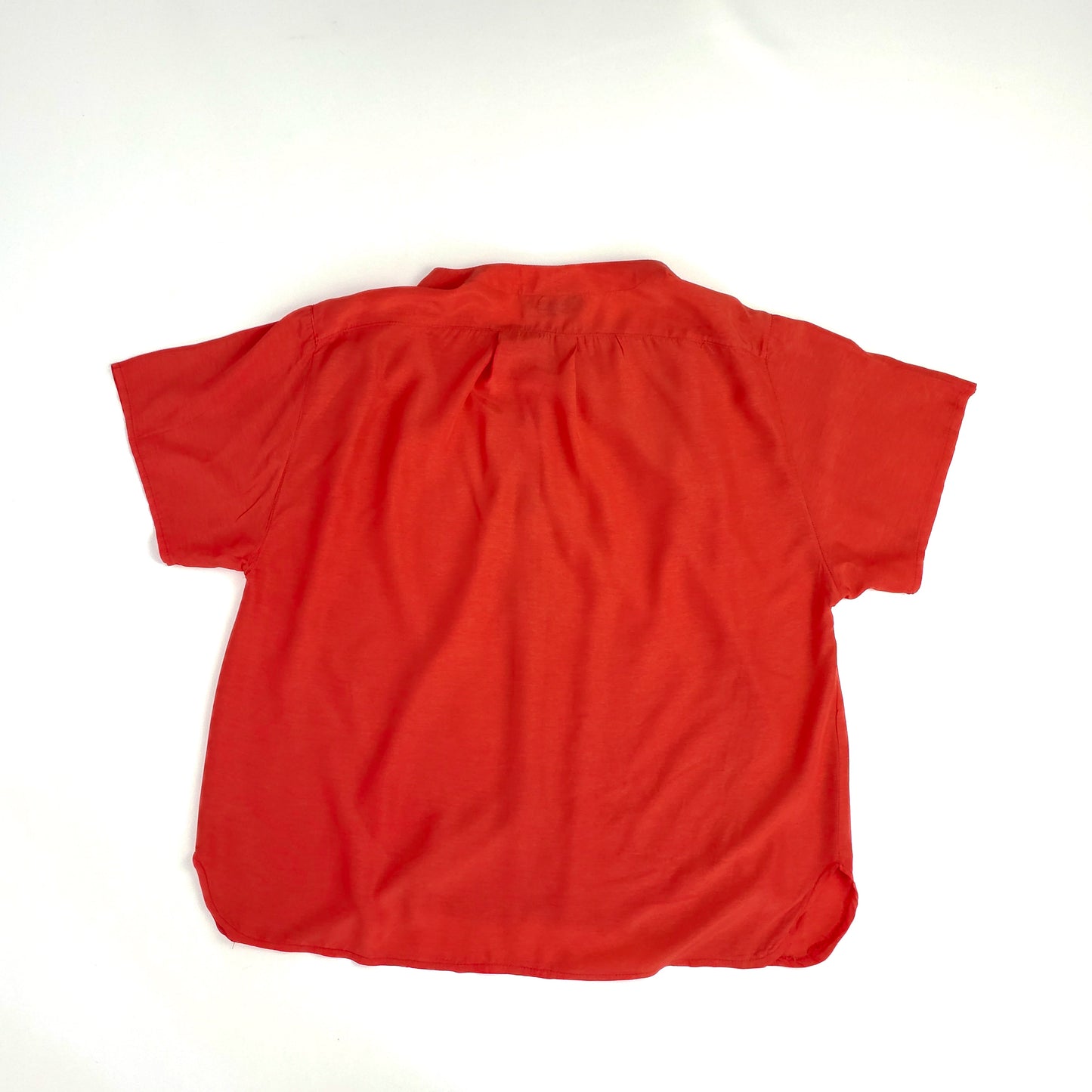 A bright red short-sleeved shirt with a collar, laid flat on a plain white surface. The shirt has a loose fit, with visible seams along the sides and back.