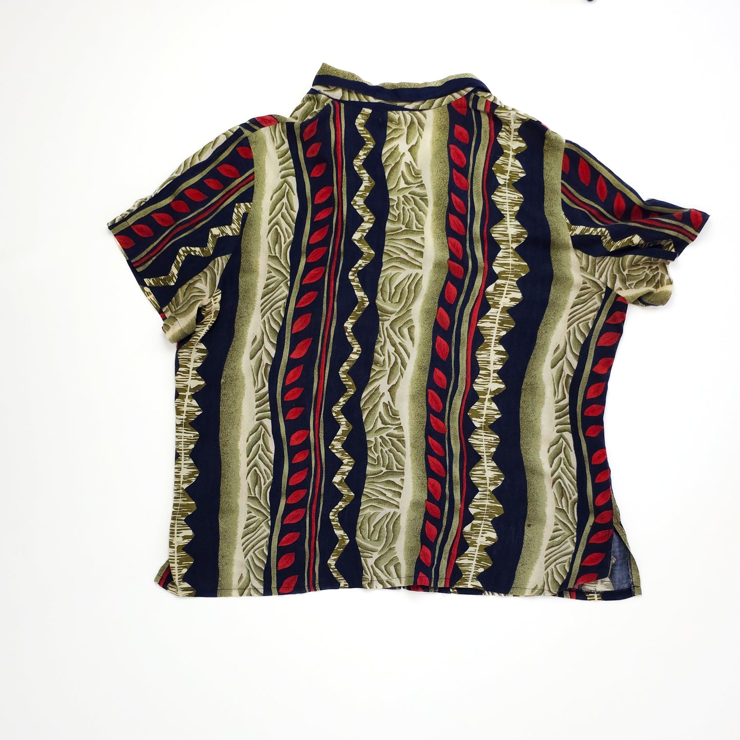 A short-sleeved shirt with bold, alternating vertical stripes in red, beige, and navy blue, featuring wavy patterns and abstract designs on a white background.