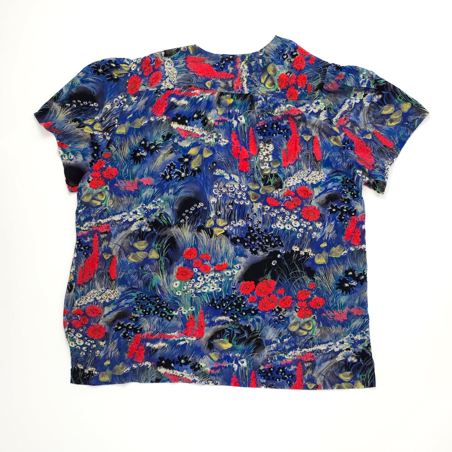 Colorful short-sleeve blouse with a nature-inspired pattern featuring vibrant red and blue florals and greenery on a dark background.