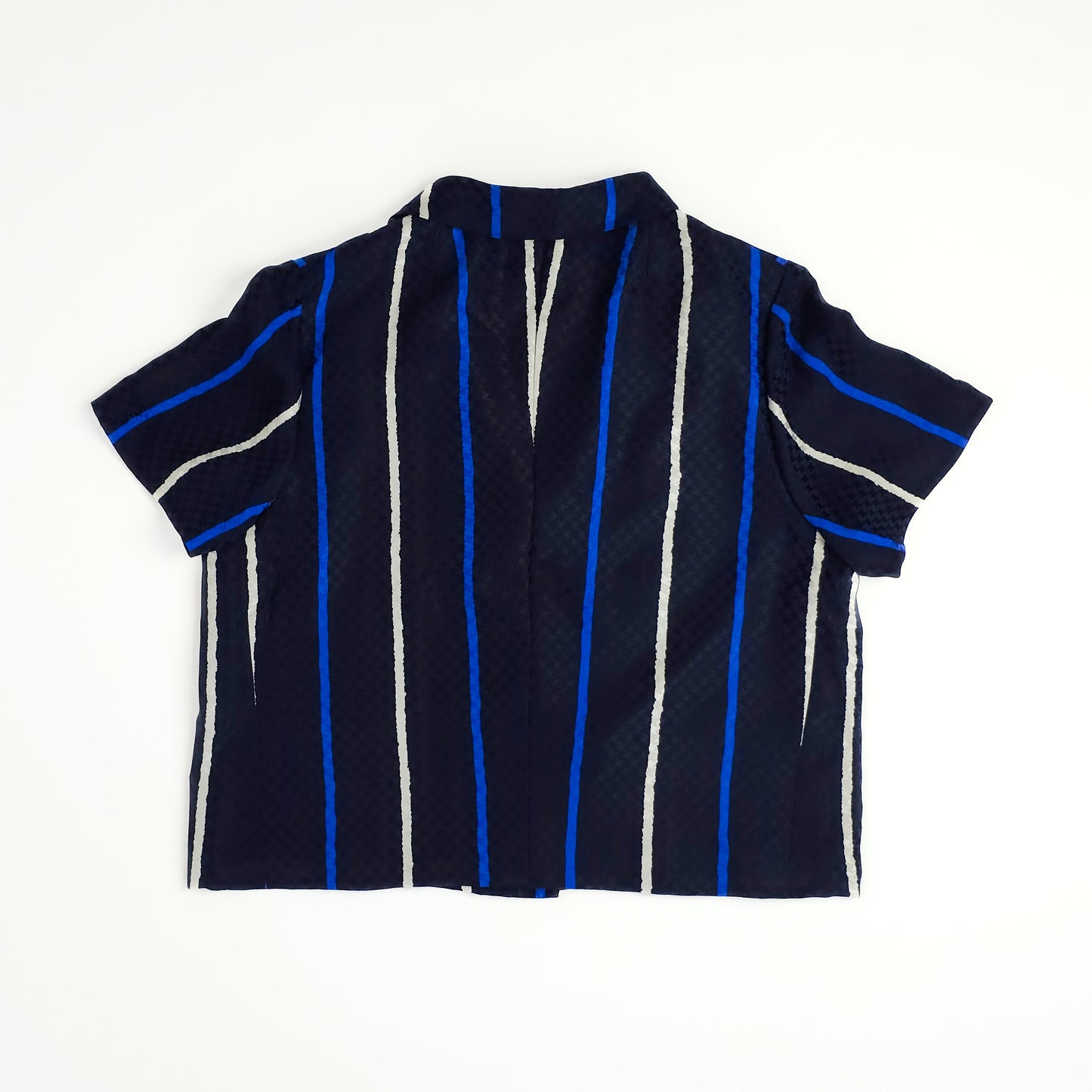 A navy blue short-sleeve shirt with vertical stripes in white and electric blue. The shirt is laid flat on a white background, showing its back.