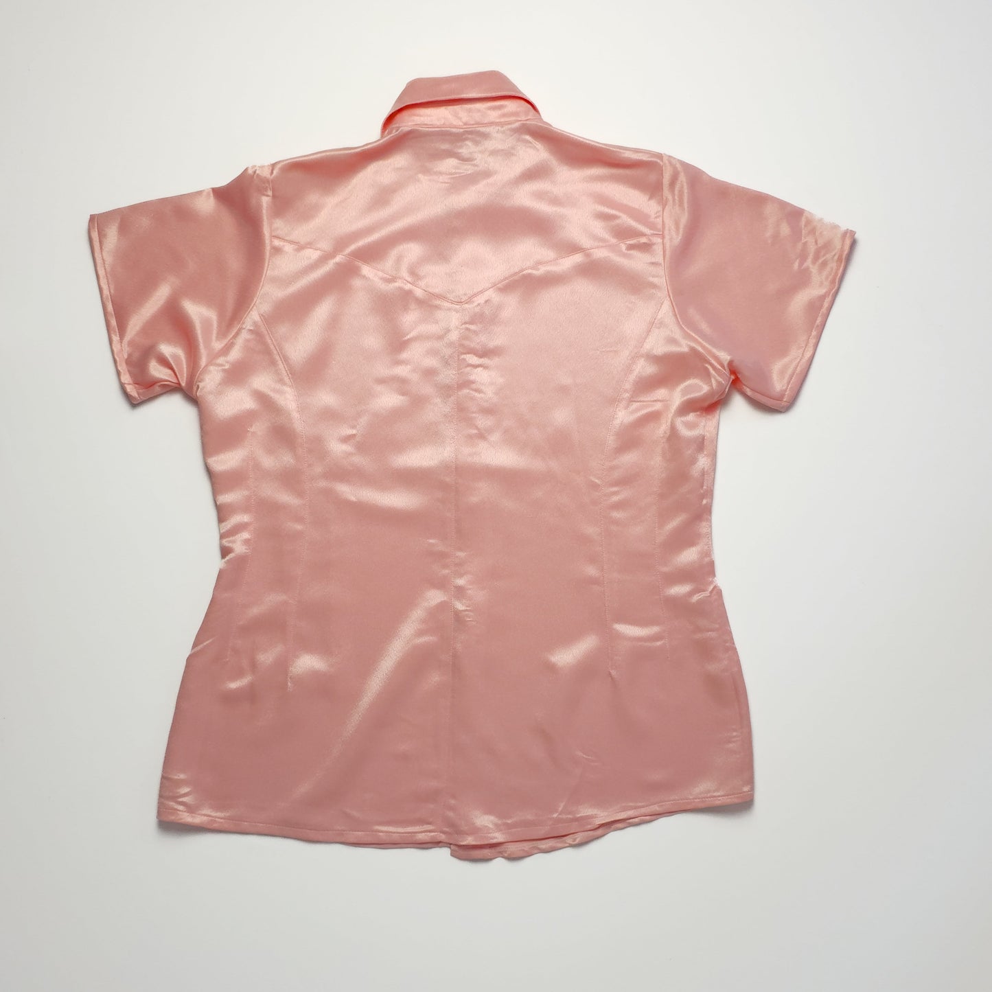 A back view of a short-sleeve pink satin blouse with a collar, showing smooth fabric and a simple design.