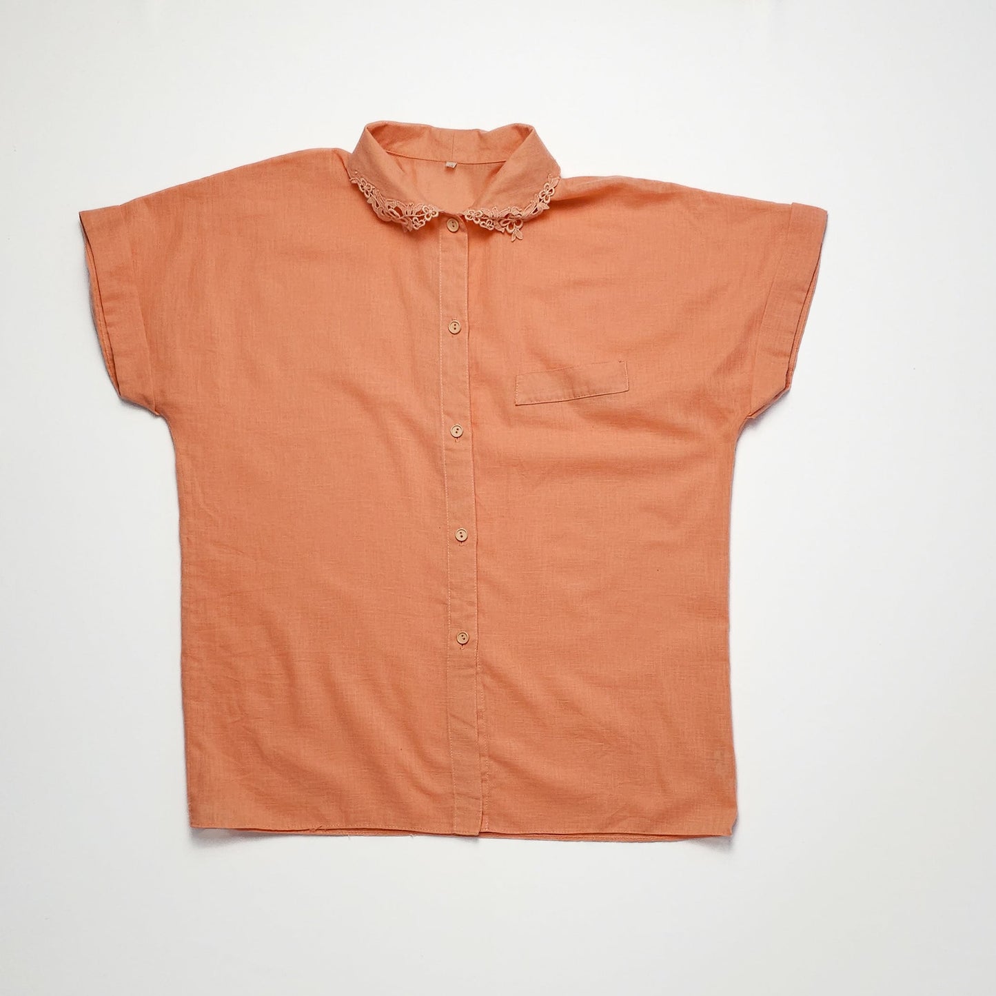 Peach blouse with lace collar and short sleeves.