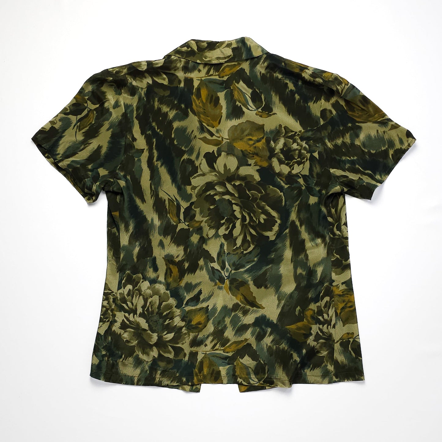 Green and black floral patterned short-sleeve shirt with a collar, laid flat with a back view. The shirt features a blend of abstract and floral designs.