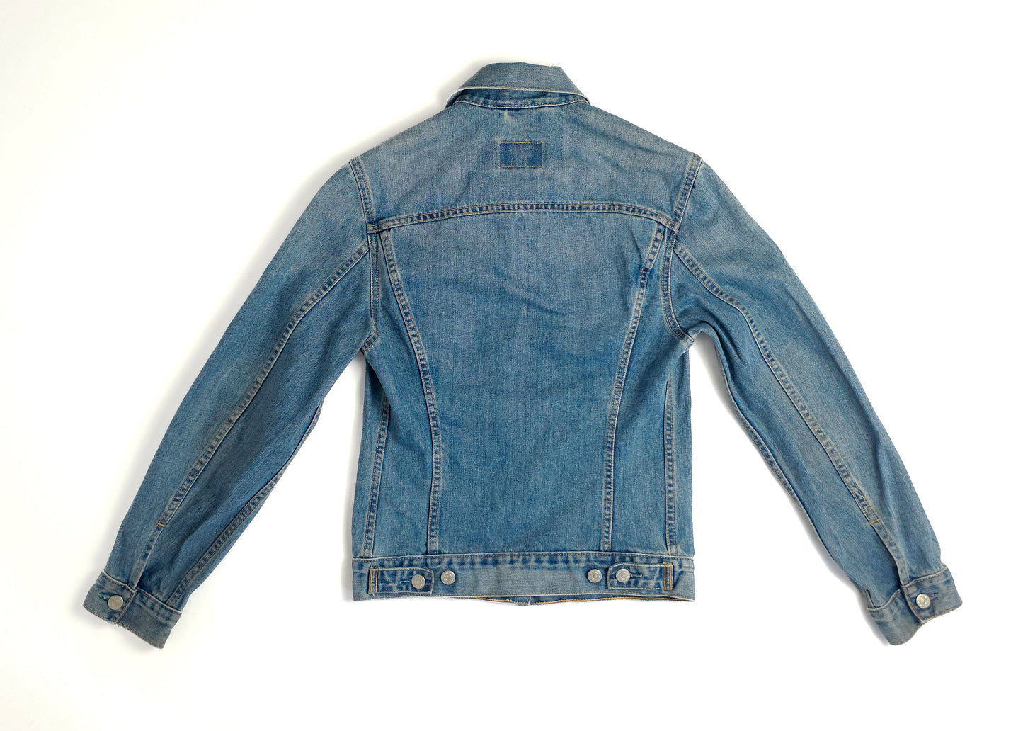 Back view of a blue denim jacket with long sleeves, buttoned cuffs, and a slightly fitted back design. The jacket has a classic light wash look.