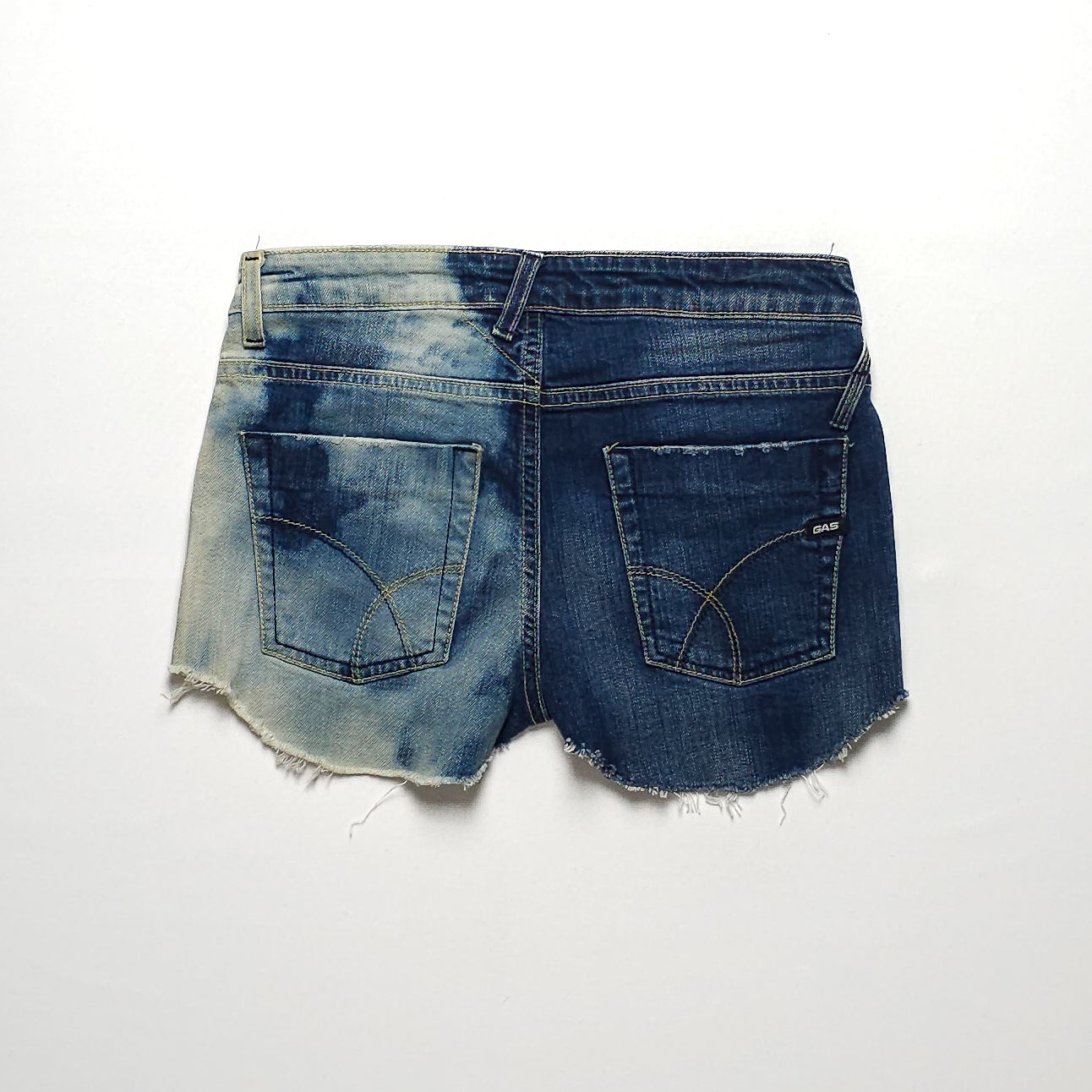 Two-tone denim shorts with a bleached left side and a dark blue right side, featuring frayed hems and back pockets with contrasting stitching details.