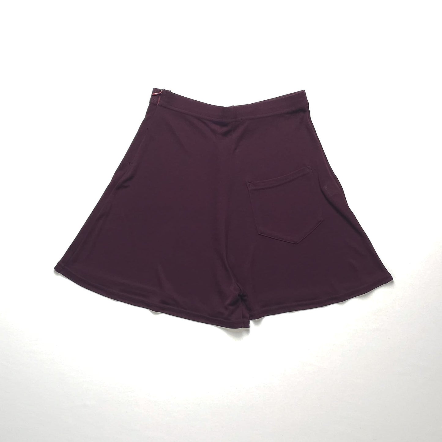 Dark reddish-purple A-line skirt with a side pocket, displayed flat on a white background. Skirt has a smooth texture and a comfortable, relaxed fit.