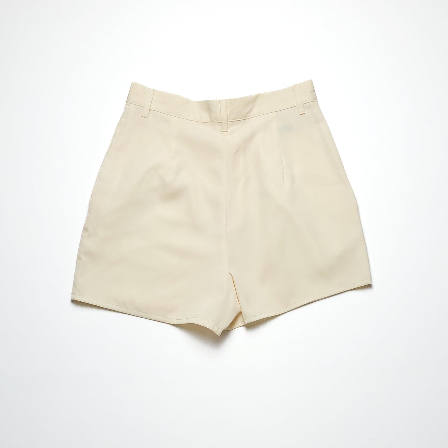 Cream-colored women's high-waisted shorts with a clean, minimalist design, featuring a flat front and two side pockets, displayed on a plain white background.