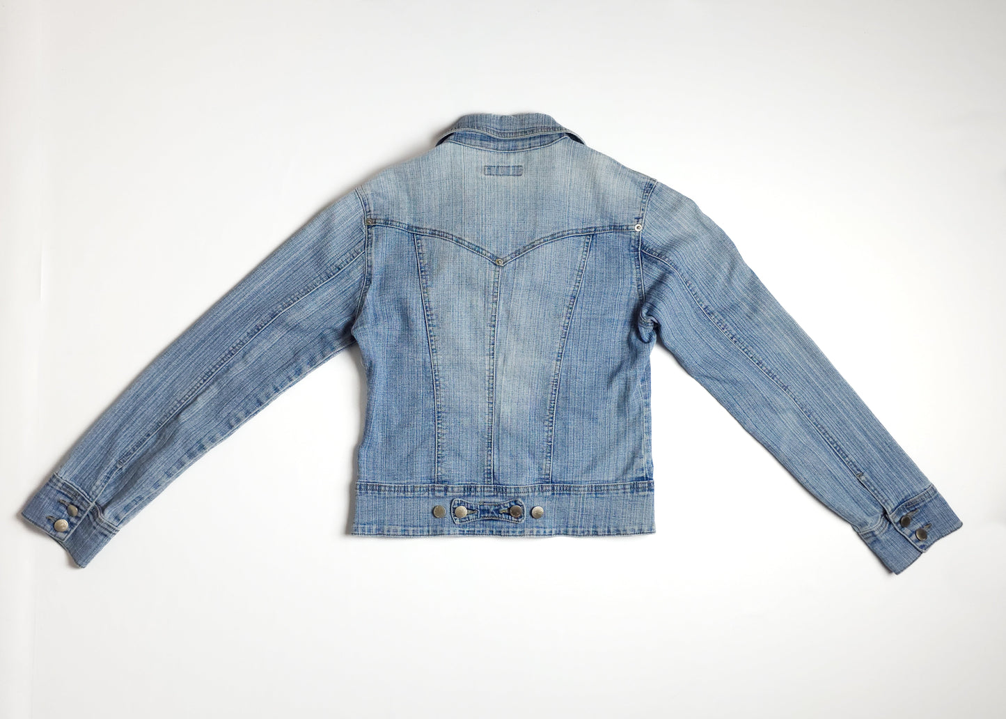 A light blue denim jacket with long sleeves and button details, photographed from the back on a plain white background.