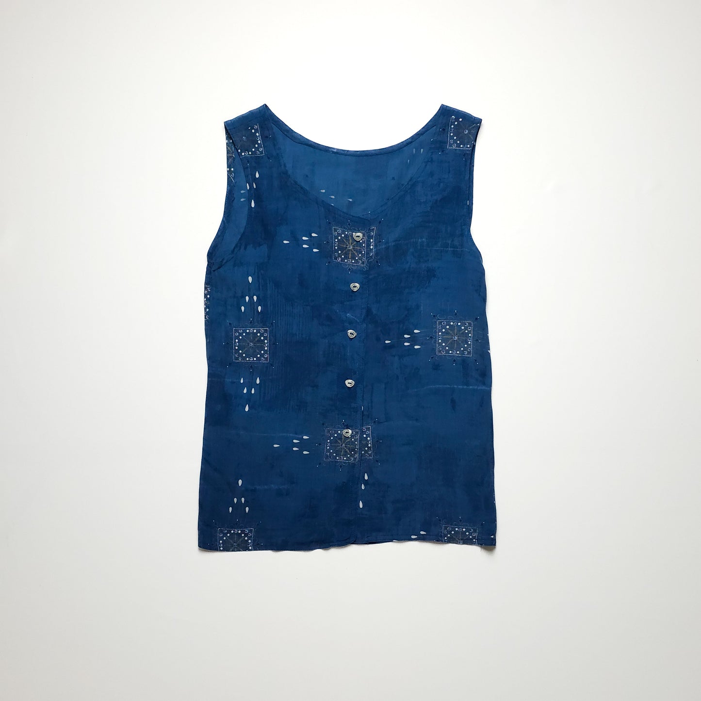 Sleeveless blue top with button-down front and decorative white stitching patterns.