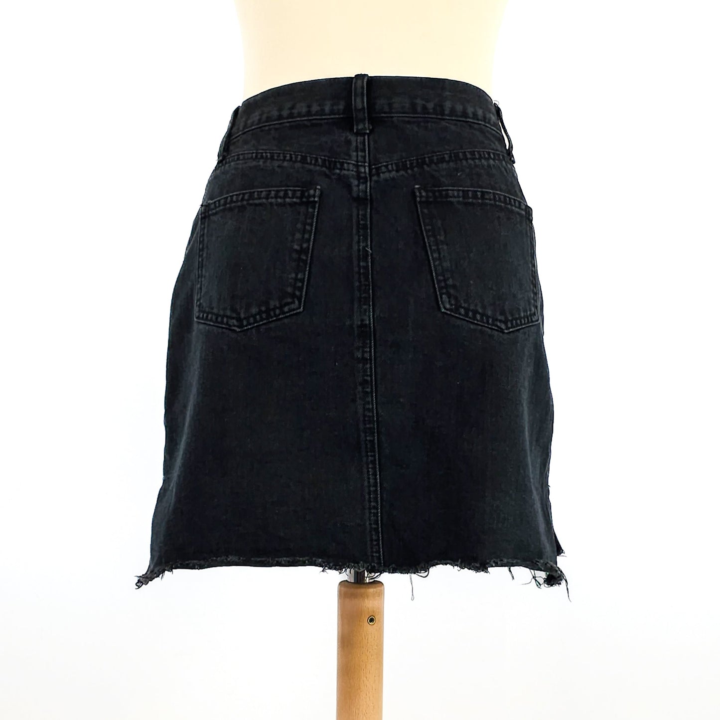 Black denim mini skirt with a frayed hem and two back pockets, displayed on a mannequin against a white background.