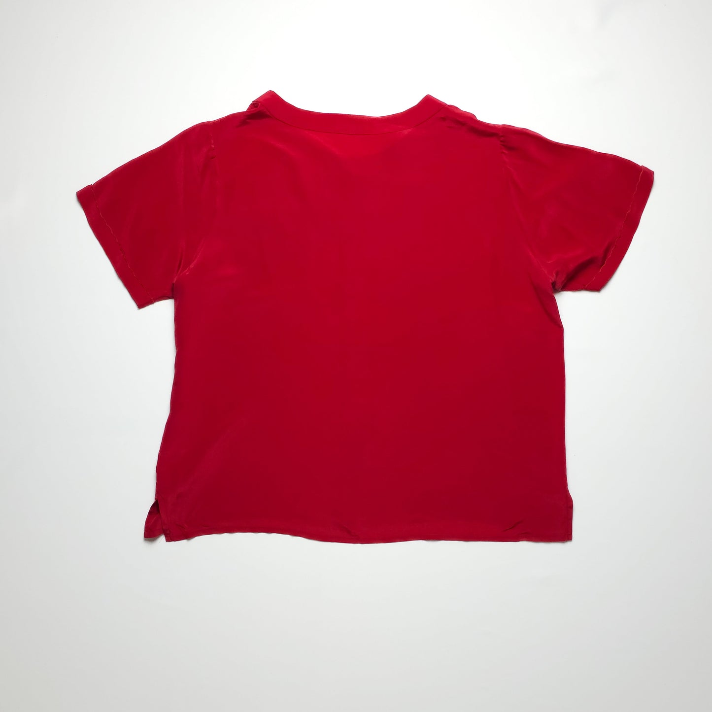 A plain red T-shirt with short sleeves and a relaxed fit, laid flat on a white background. The fabric appears soft and slightly textured.