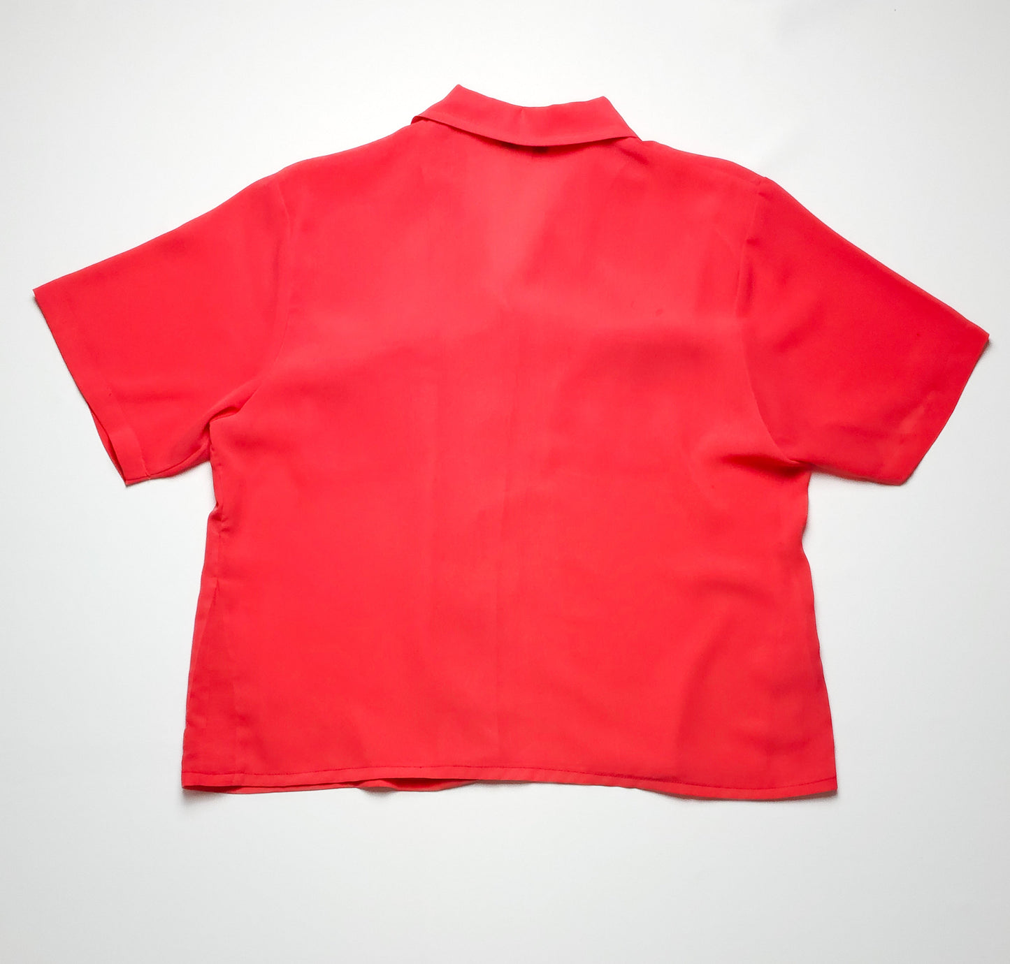 A bright red, short-sleeved button-up shirt displayed with its back facing the camera, featuring a classic collar and a loose fit, on a white background.