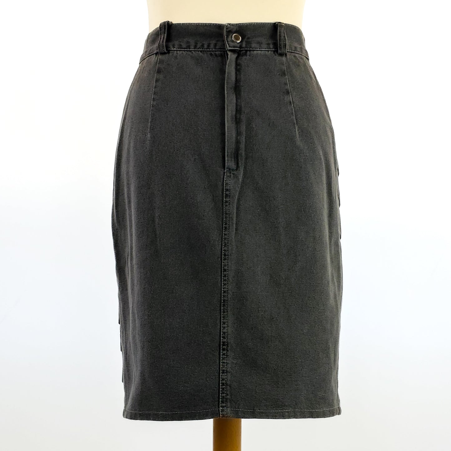 A knee-length dark gray denim skirt displayed on a mannequin, featuring a front button and zip closure with a subtle A-line silhouette.