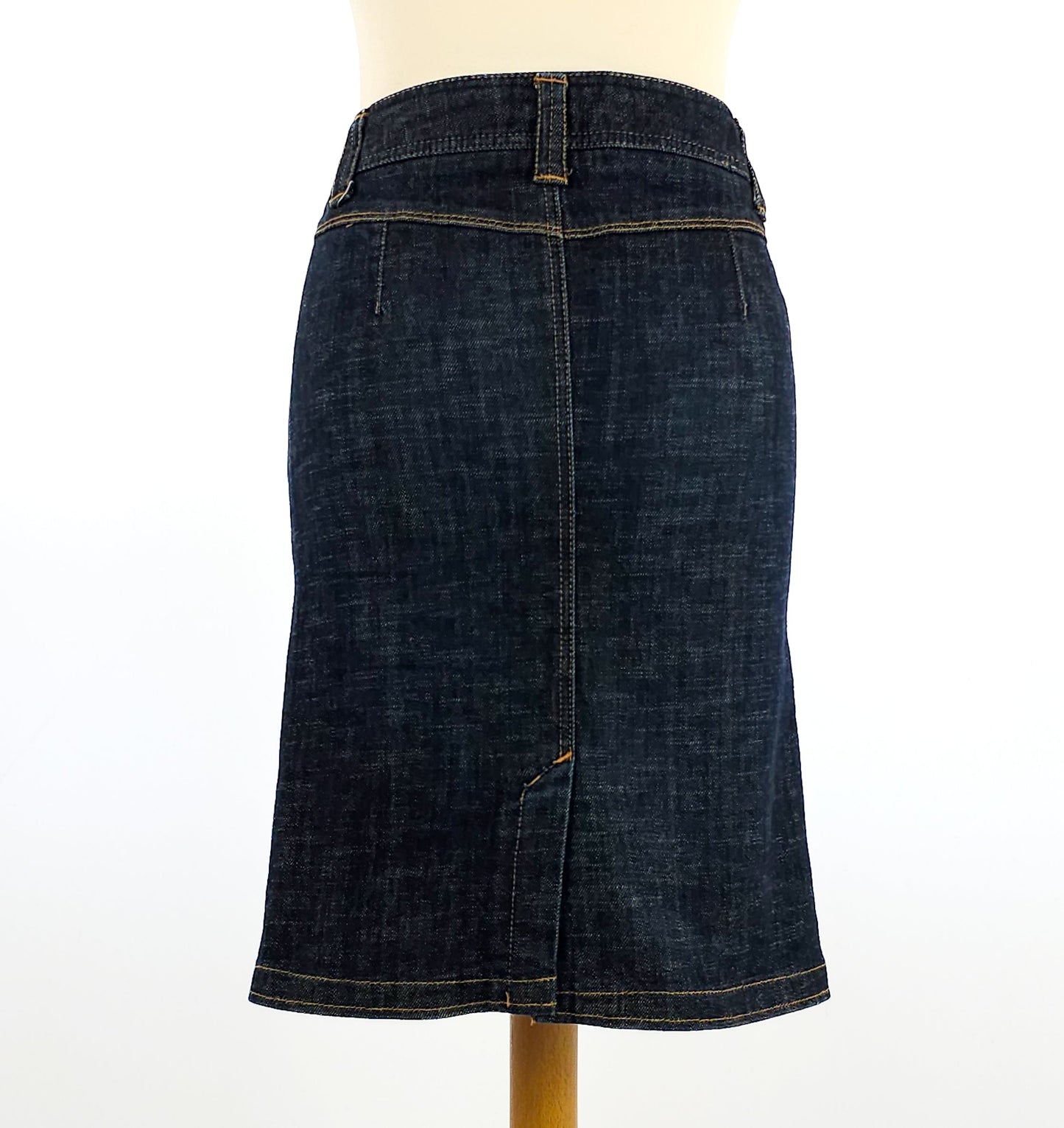 Dark denim pencil skirt displayed on a mannequin, featuring stitching details and a rear slit for style and comfort.