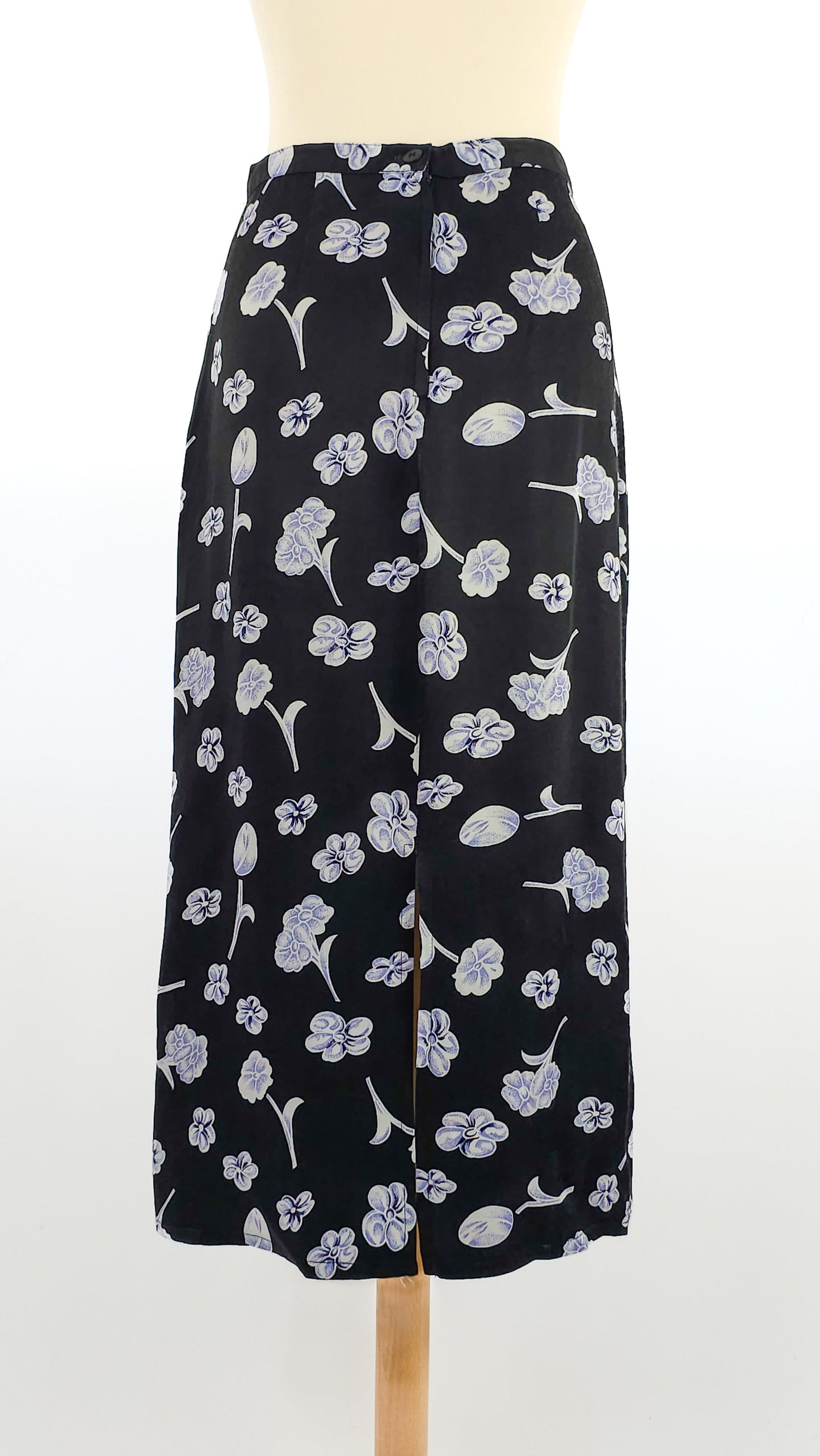 Long black skirt with a floral pattern, featuring light blue and white flowers, displayed on a mannequin against a plain background.