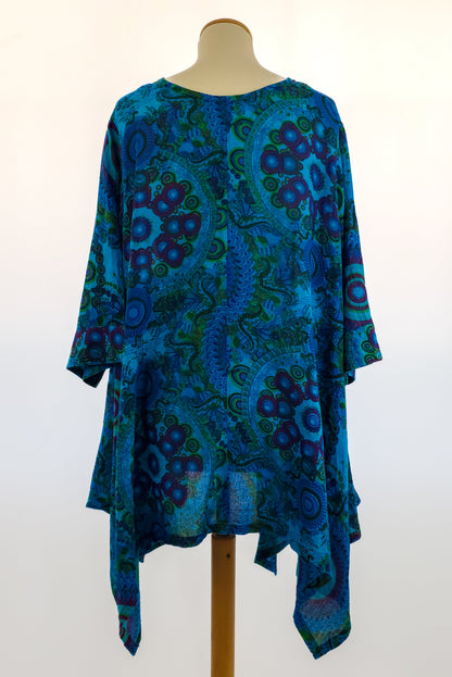 Blue and green bohemian tunic with vibrant circular and swirl patterns, three-quarter sleeves, and an asymmetrical hem, displayed on a mannequin.