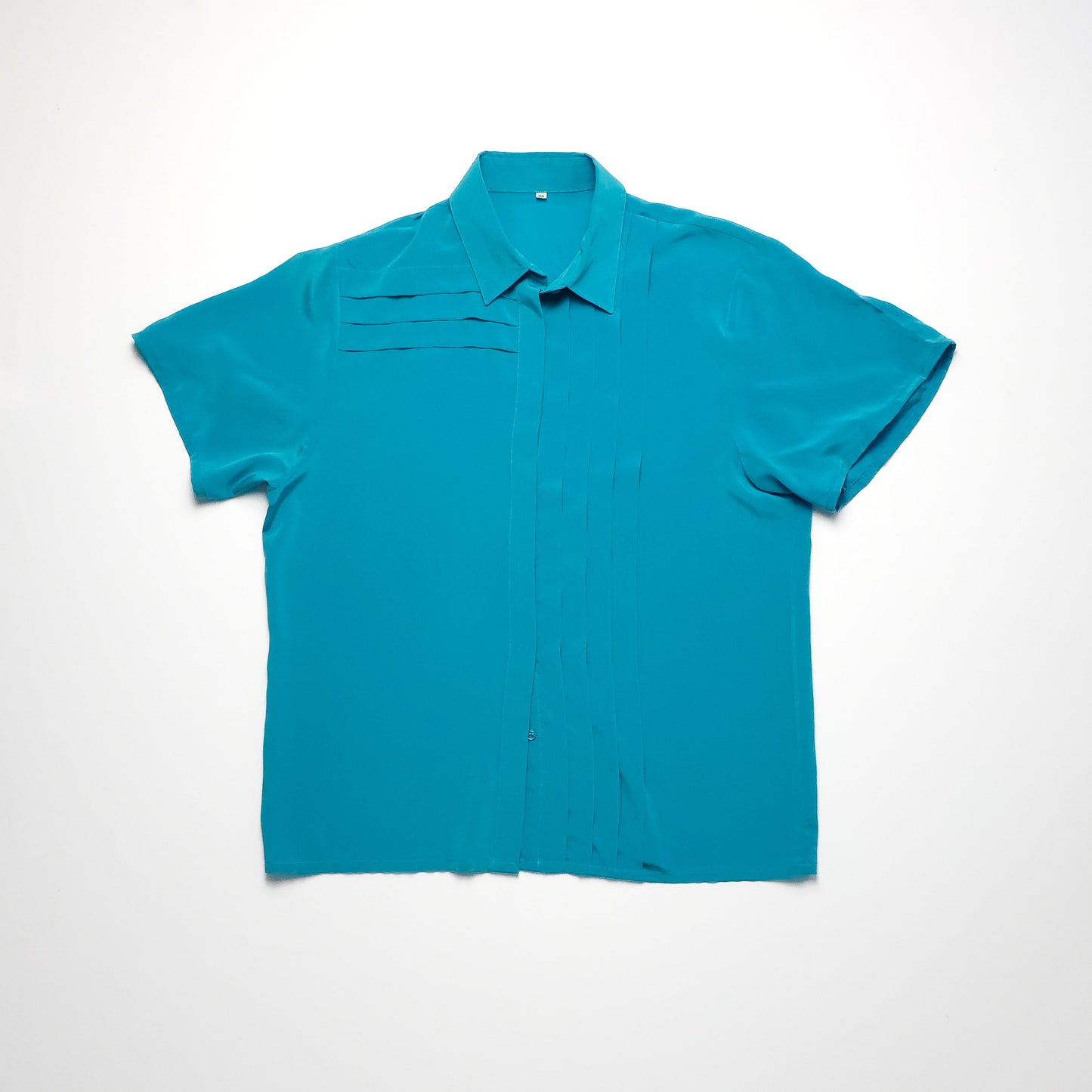 Teal short-sleeve blouse with a pointed collar and subtle pleated details on the front.
