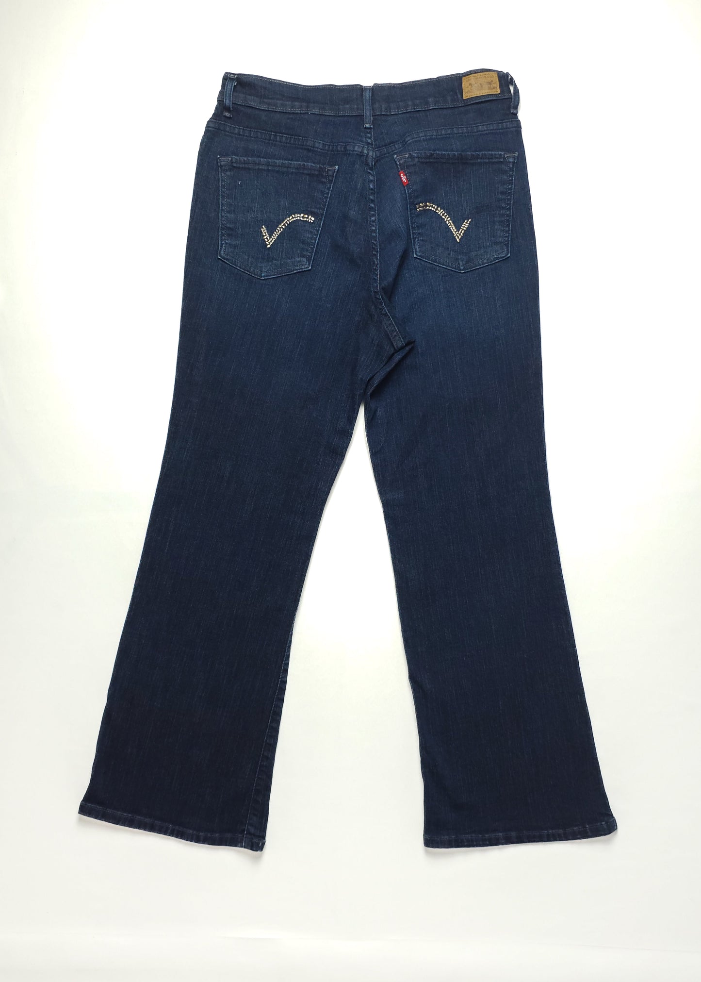 Dark blue vintage jeans with flared legs and back pocket embroidery featuring a stylized "V" design. Jeans are laid flat on a white background.