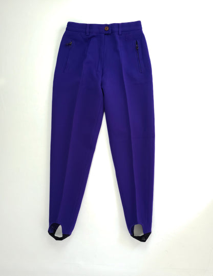 Indigo-colored stirrup leggings with a button closure and zippered pockets.